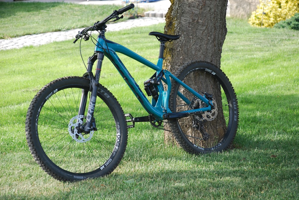a blue mountain bike leaning against a tree