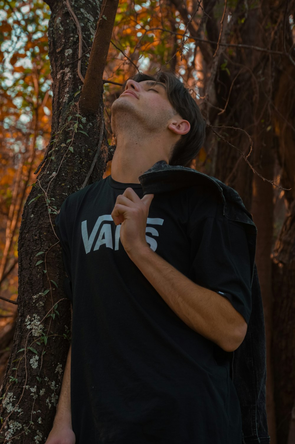 a man standing next to a tree in a forest