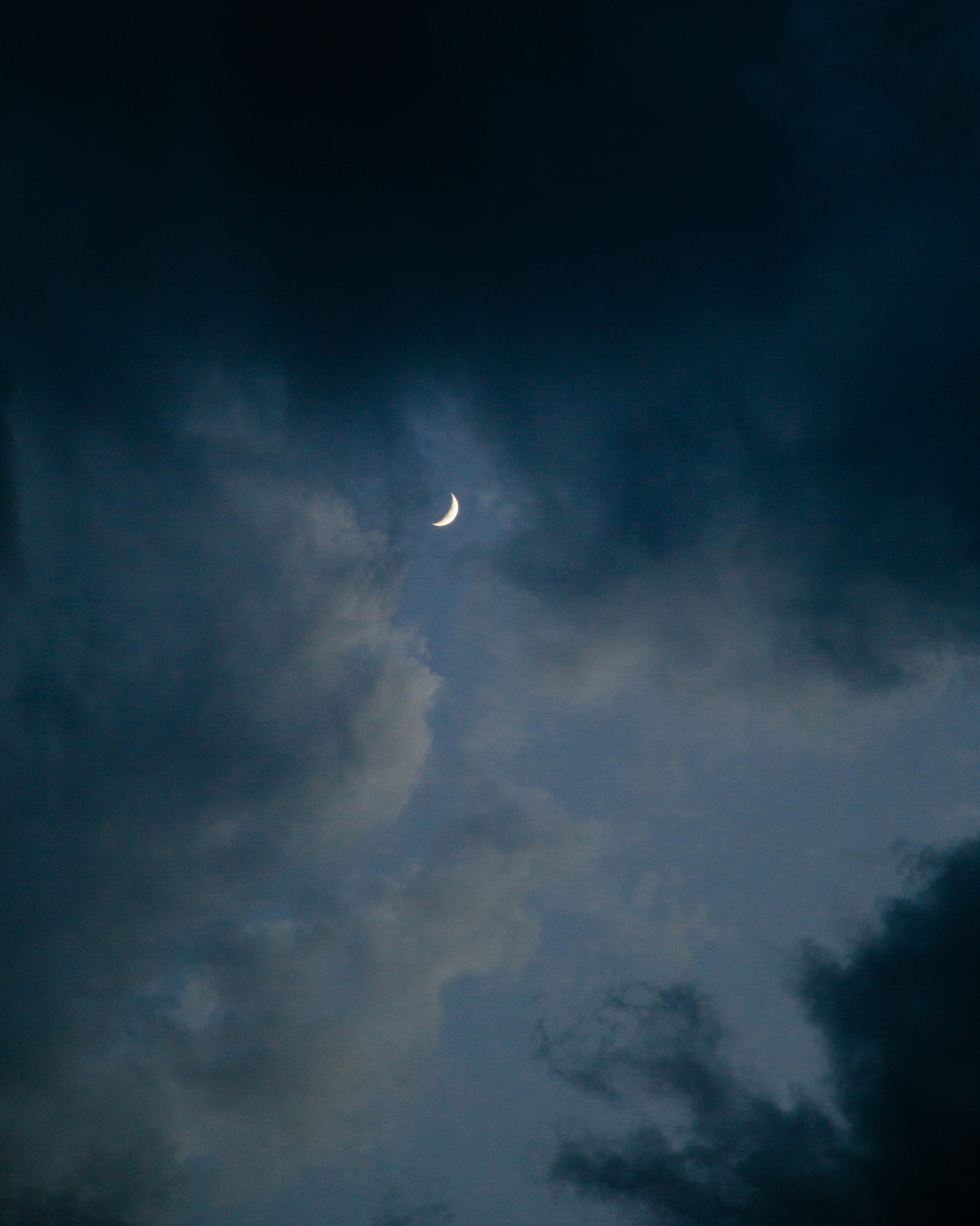 the moon is seen through the dark clouds