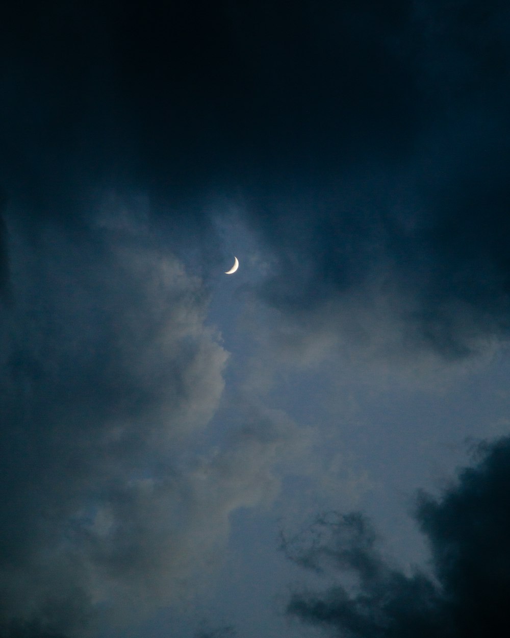 the moon is seen through the dark clouds