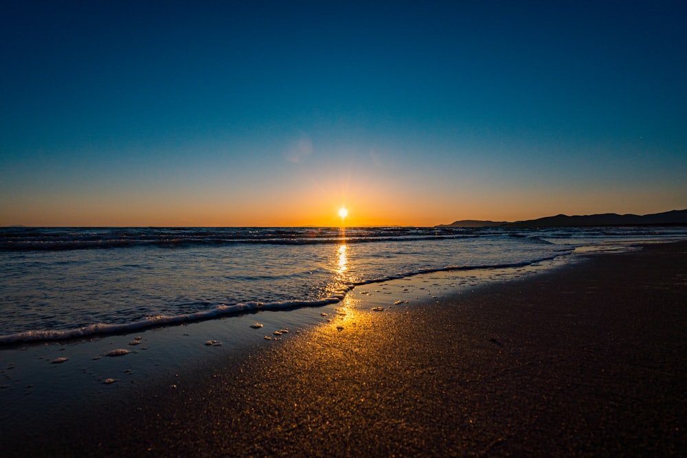 il sole sta tramontando sull'acqua sulla spiaggia