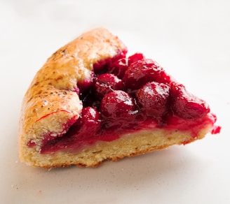 Close-up of a moist chocolate cake slice with creamy frosting and a cherry on top.