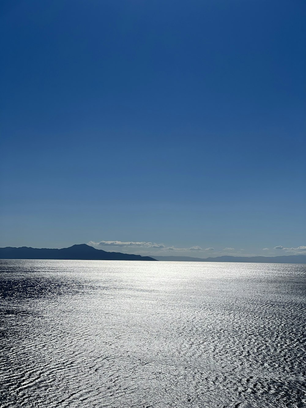 a large body of water sitting under a blue sky