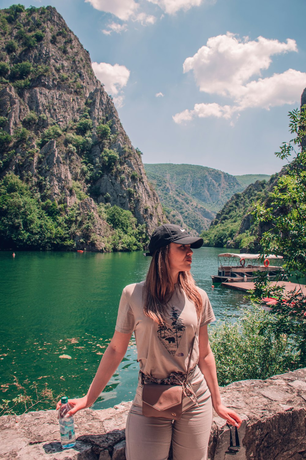 a woman standing on the edge of a cliff next to a body of water