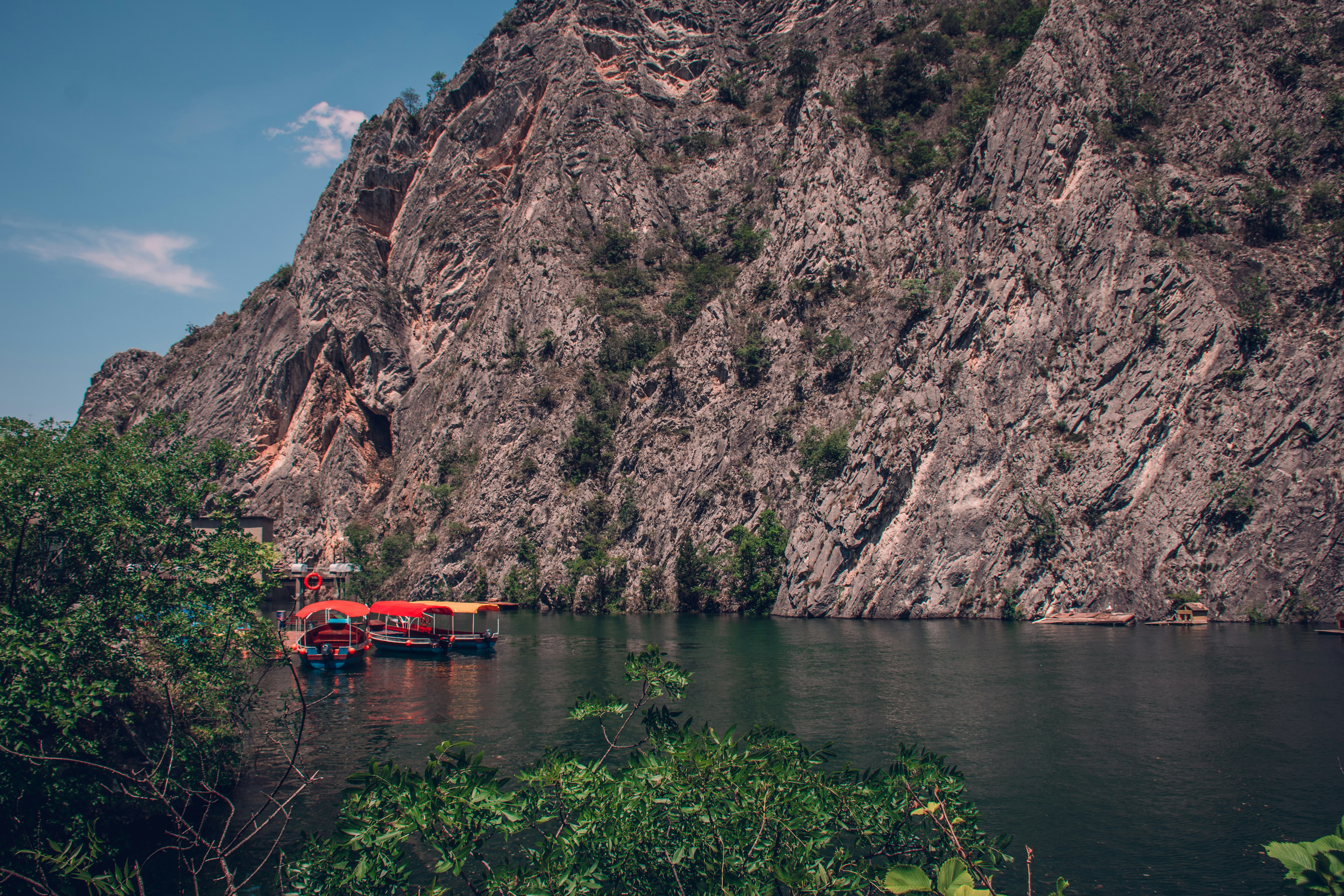perahu mengapung di atas danau di sebelah gunung