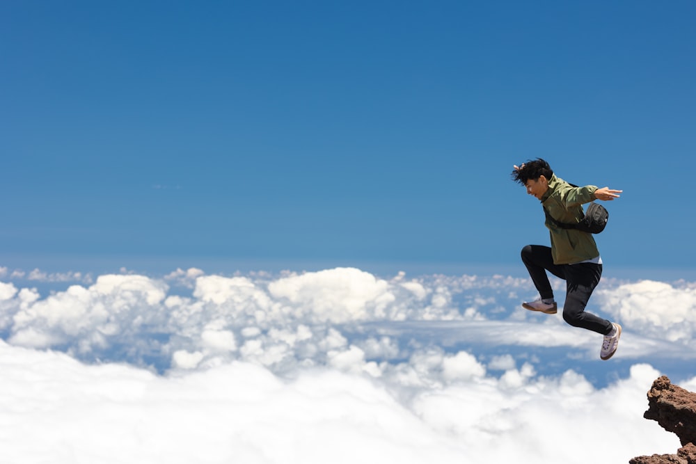 a man jumping in the air on top of a mountain