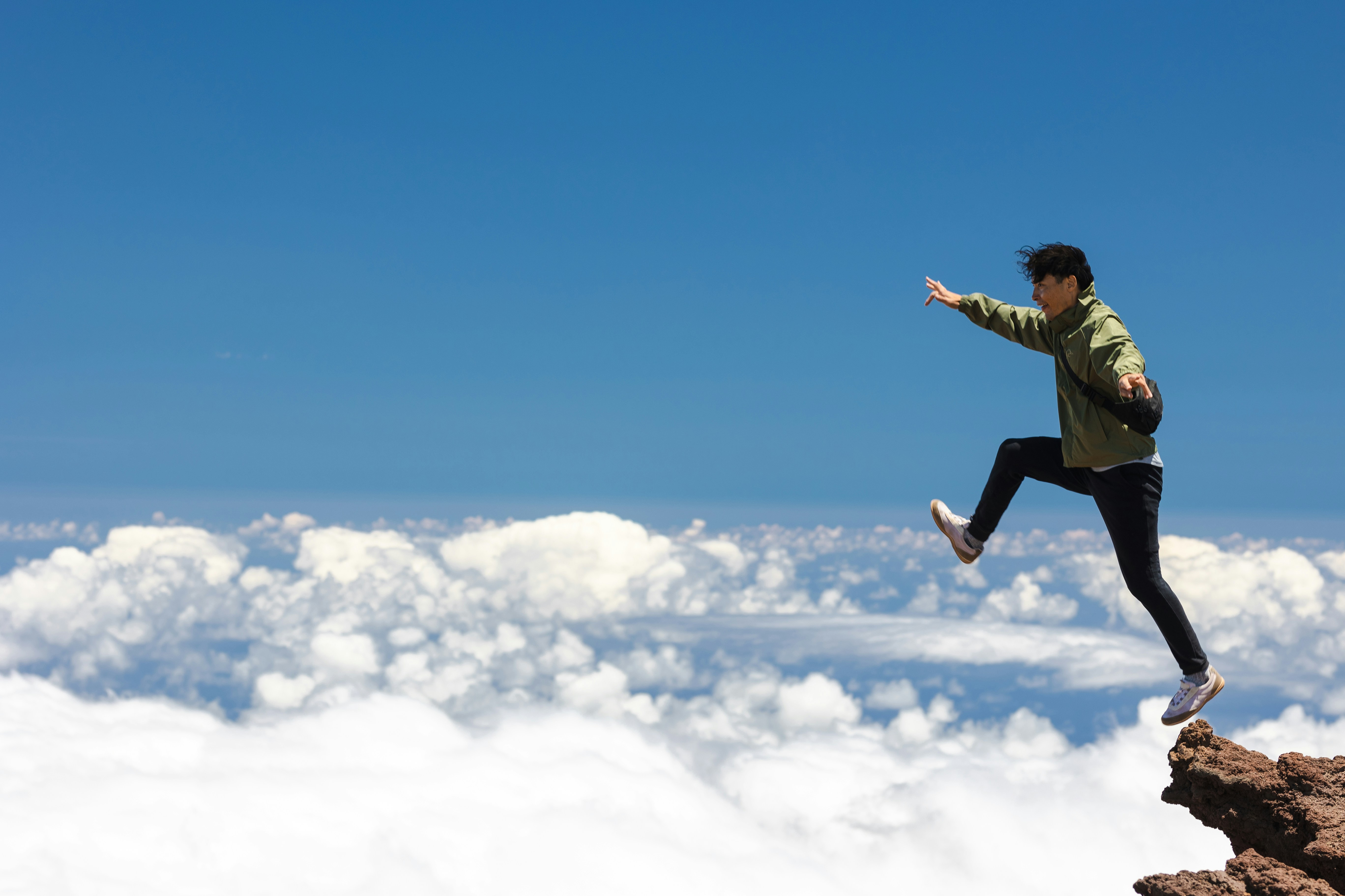 A guy is jumping from rock cliff showing his passion and joy. The picture was taken in Halekala, the highest mountain in Hawaii.
