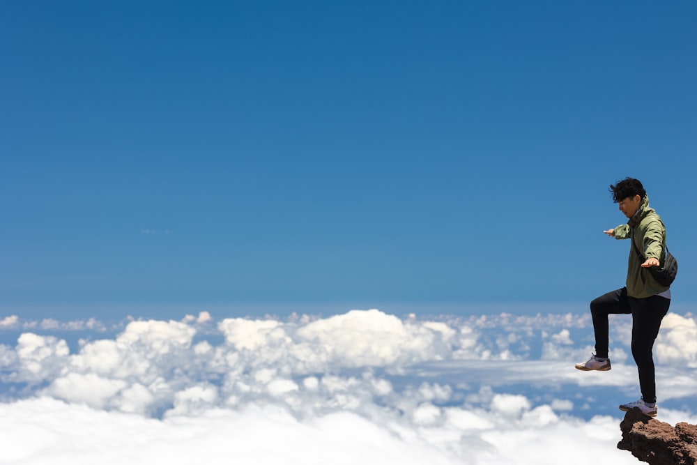 a man standing on top of a cliff above the clouds
