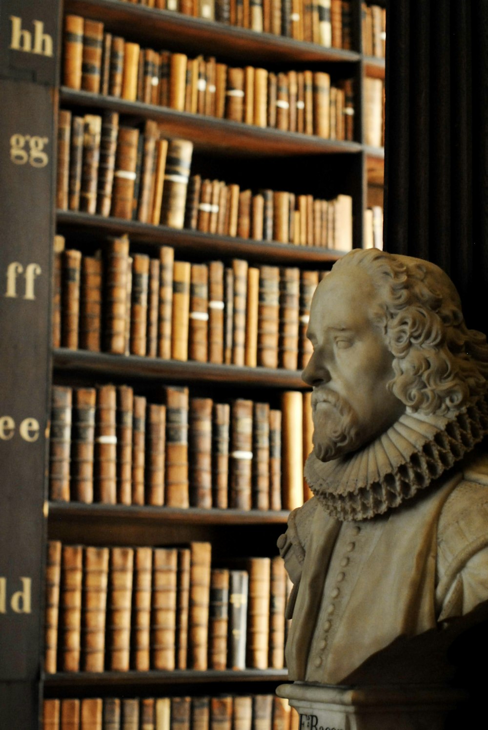 a bust of a man in front of a bookshelf