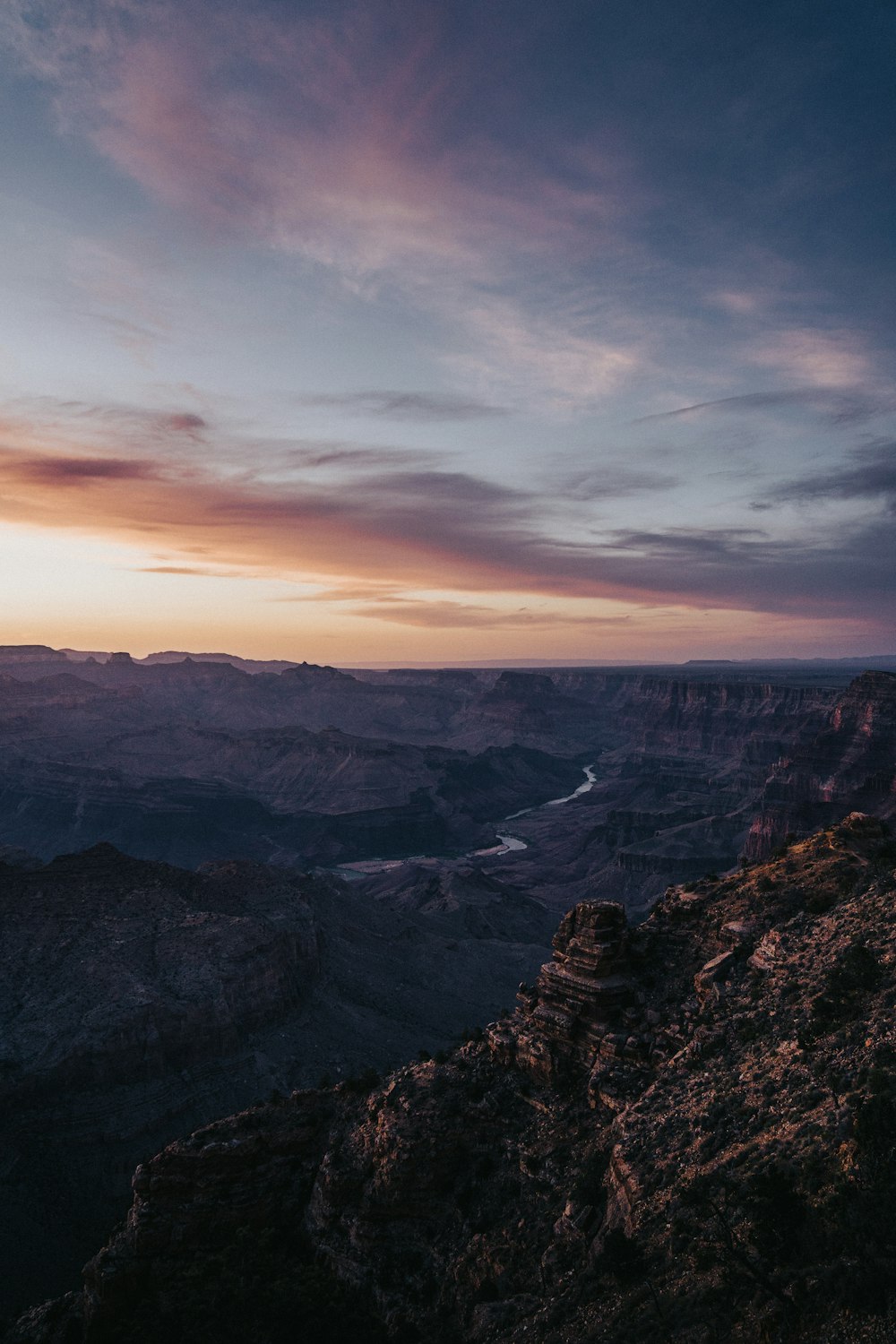 a person sitting on a cliff overlooking a river