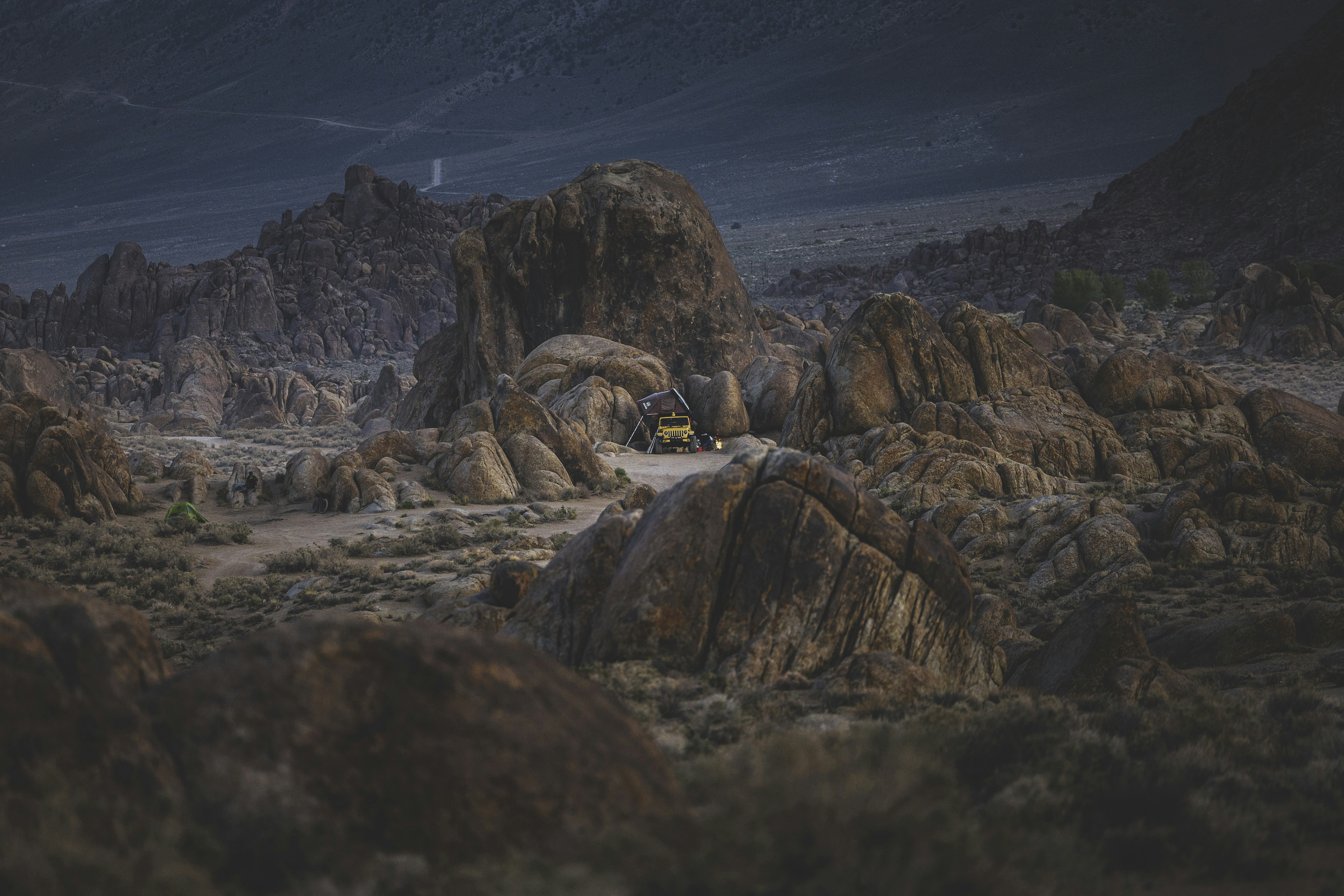 a yellow truck driving through a rocky landscape