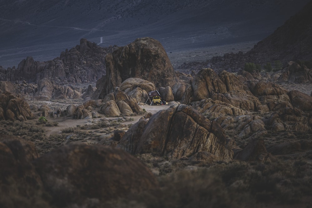 a yellow truck driving through a rocky landscape