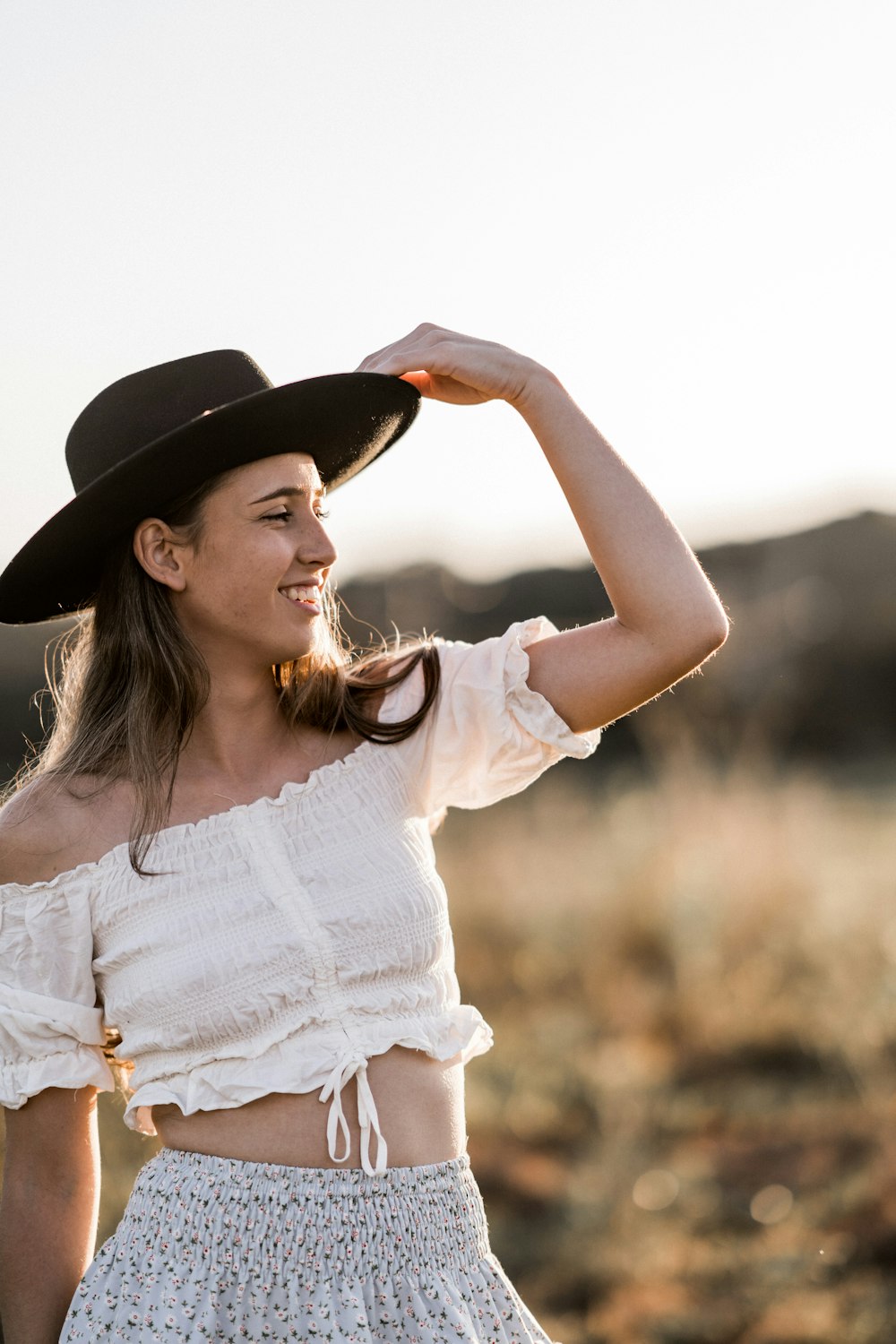 a woman wearing a white top and a black hat