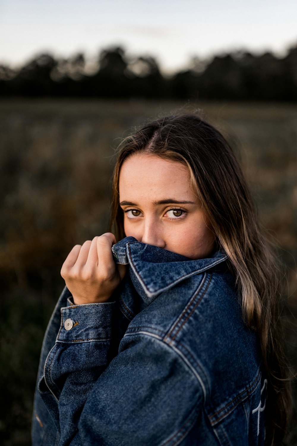 a woman covering her face with a jean jacket