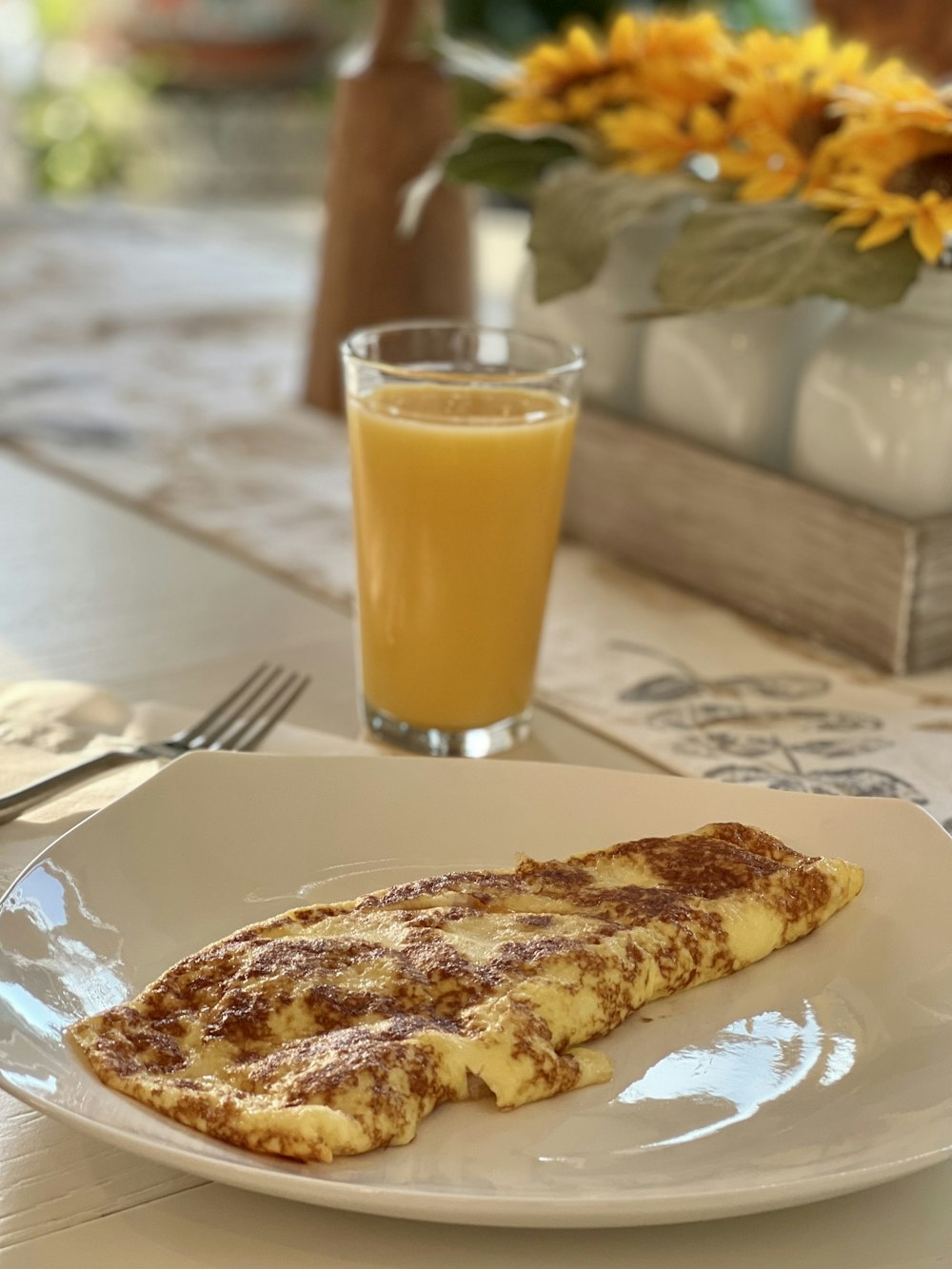 un plato blanco cubierto con comida junto a un vaso de jugo de naranja