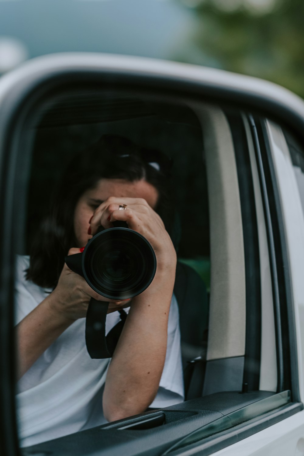 a woman taking a picture of herself in a car mirror