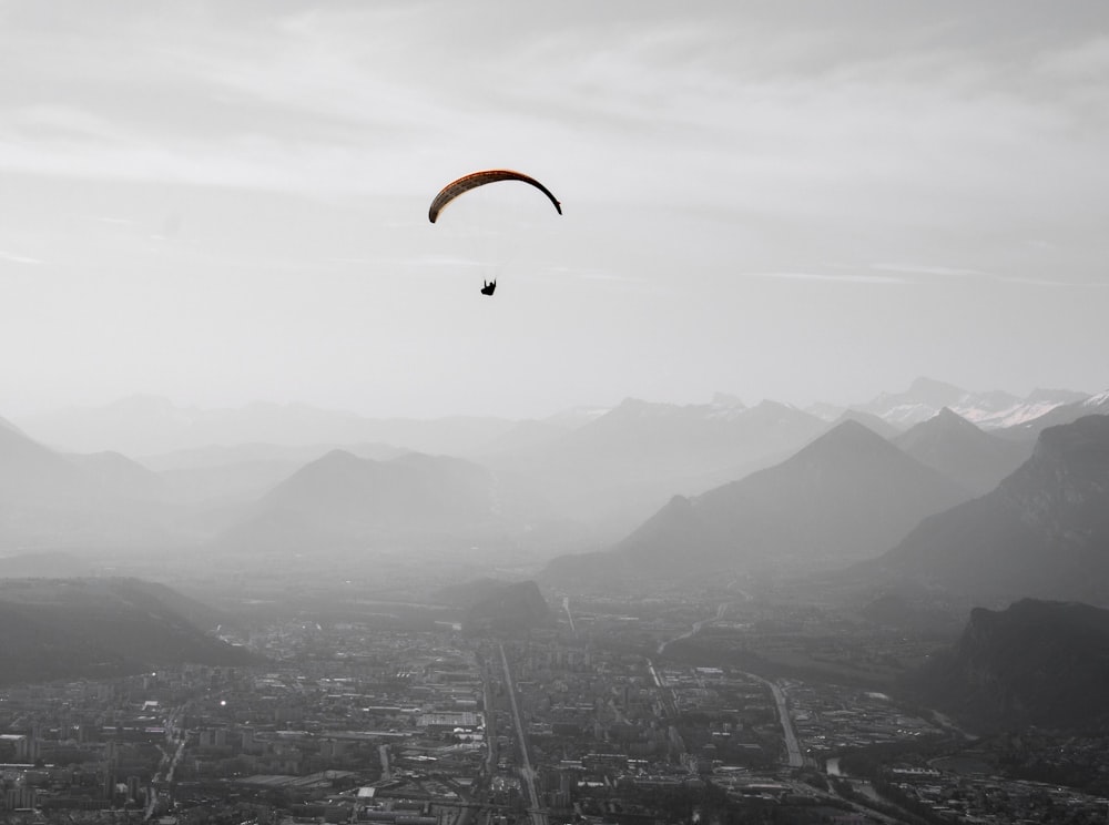 a paraglider flies over a city in the mountains
