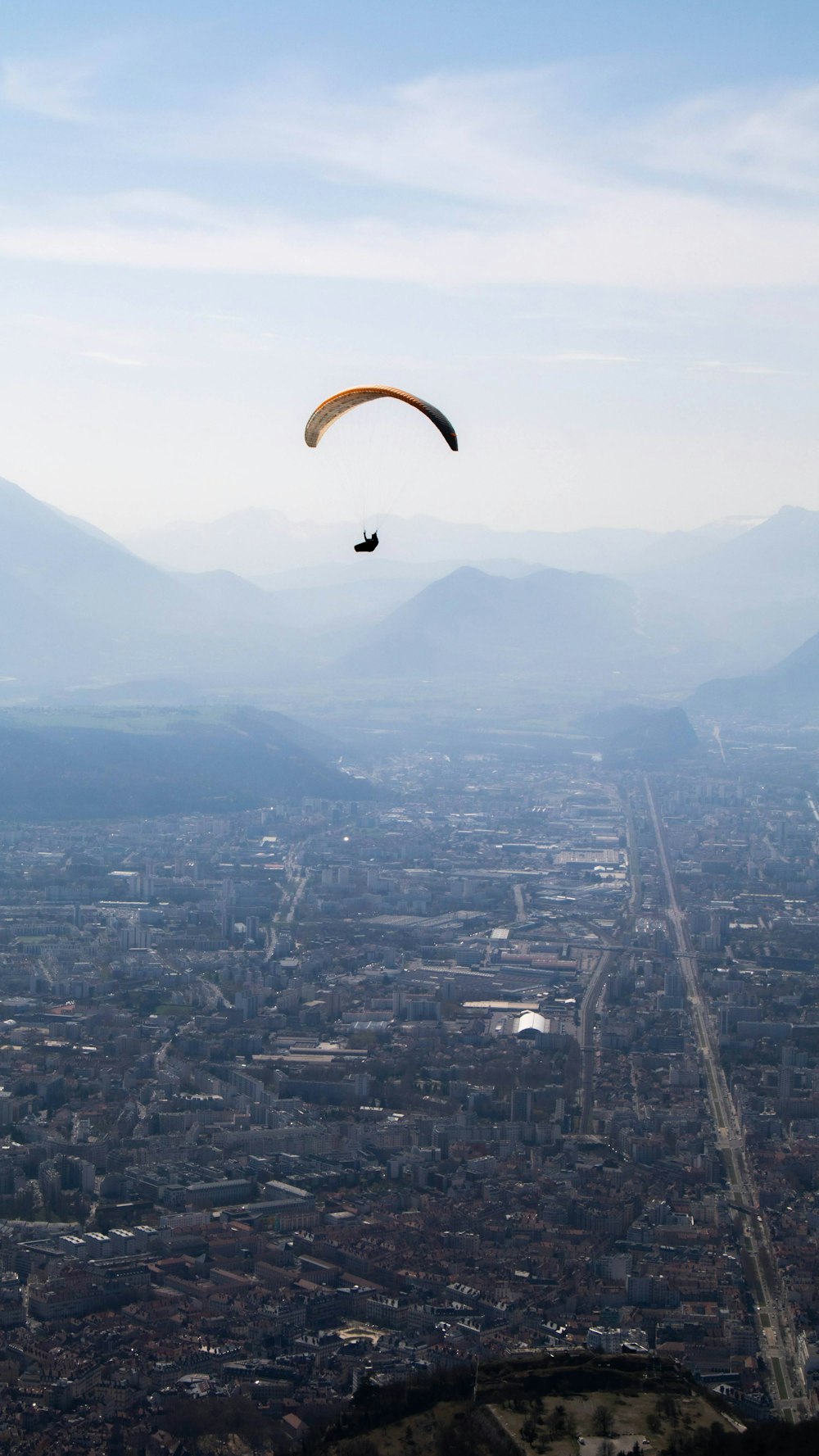 a paraglider flying over a city with mountains in the background
