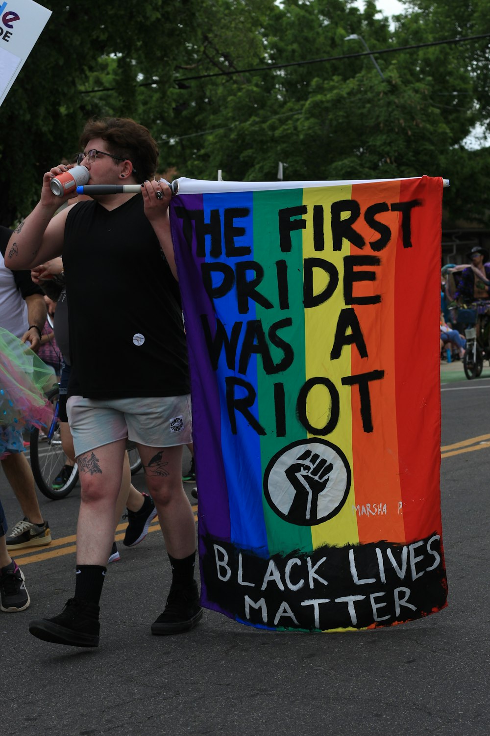 a man standing next to a rainbow flag