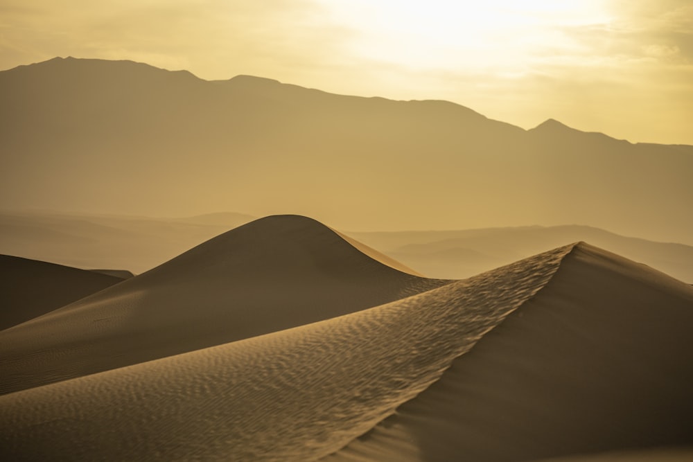 the sun is setting over the sand dunes