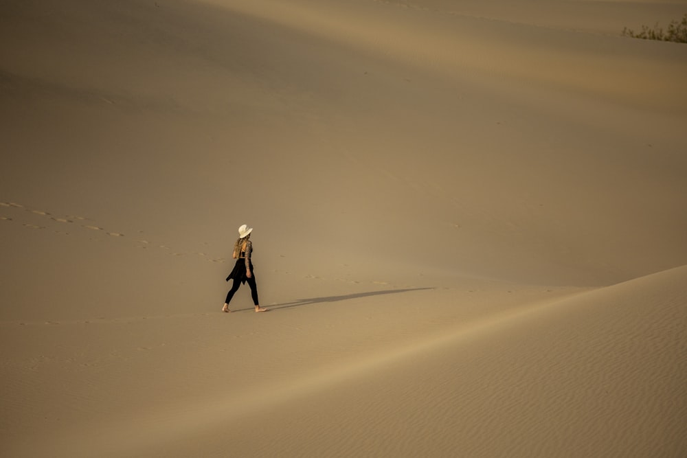 a person walking across a large sand dune