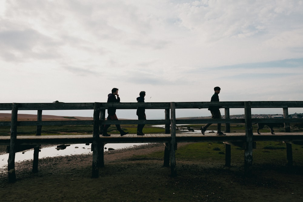 a group of people walking across a bridge