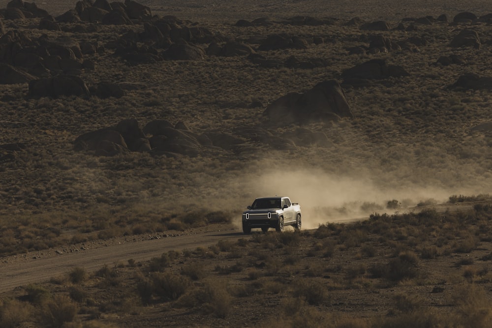 a white truck driving down a dirt road