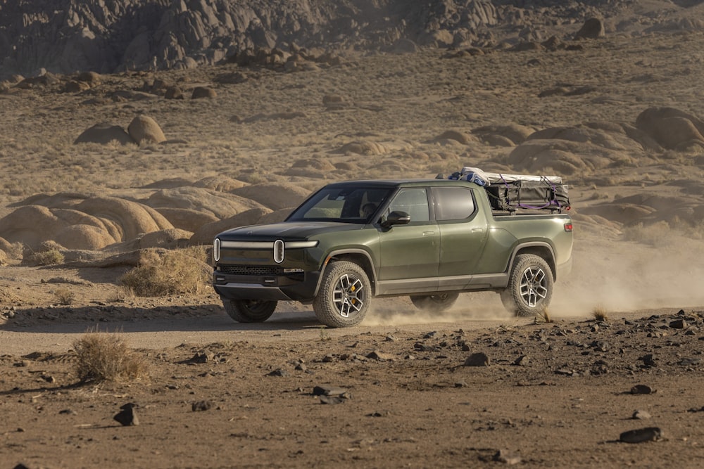 a green truck driving down a dirt road