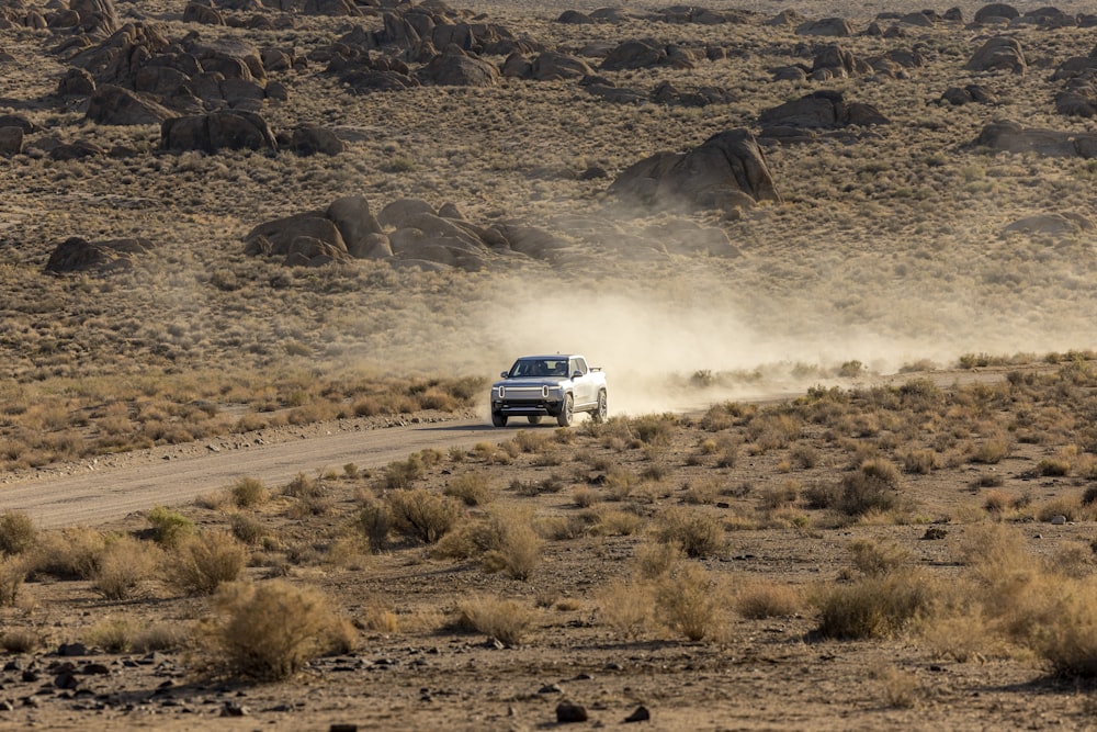 a white truck driving down a dirt road