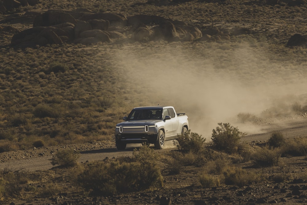 a white truck driving down a dirt road