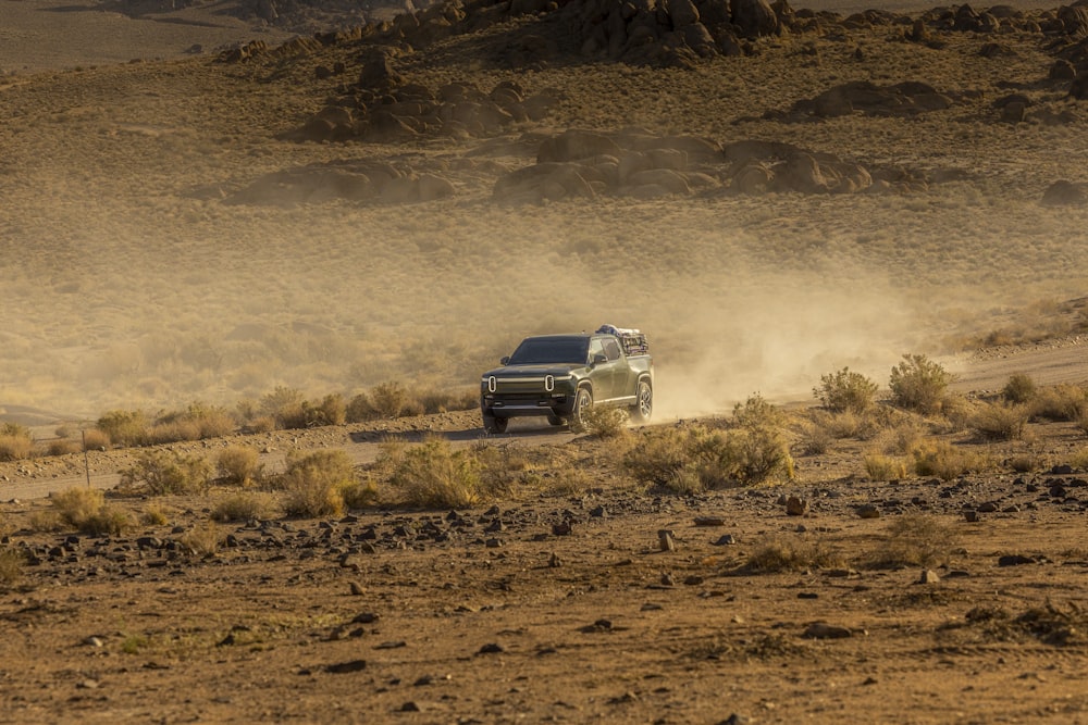 a truck driving on a dirt road in the desert