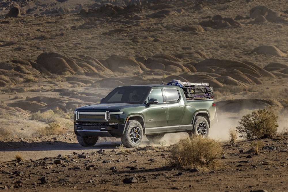 a green truck driving down a dirt road