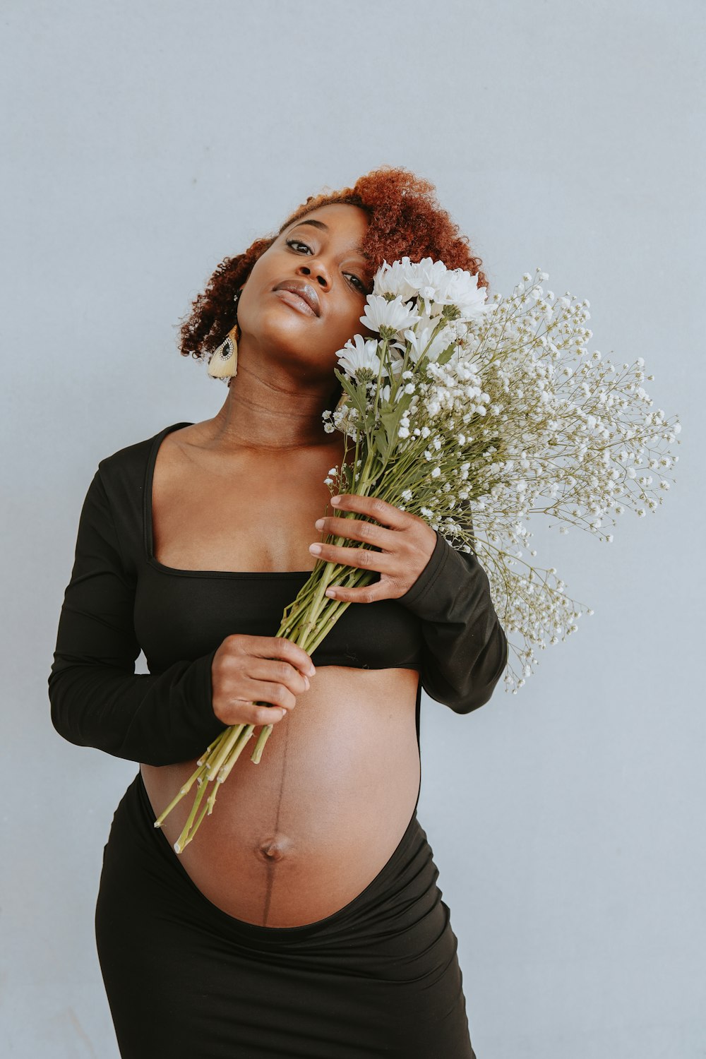 a pregnant woman holding a bouquet of flowers