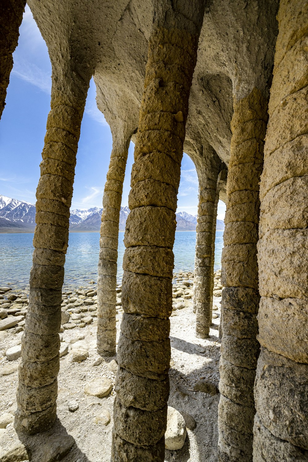 a row of stone pillars next to a body of water
