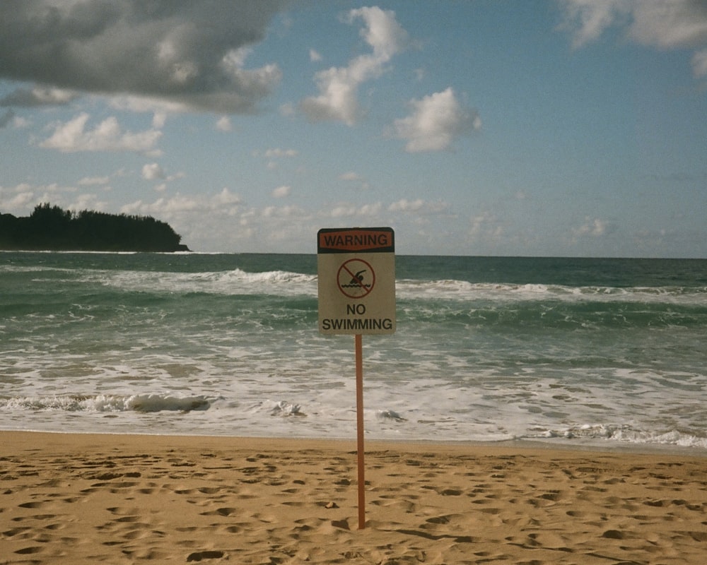 a no swimming sign on a sandy beach