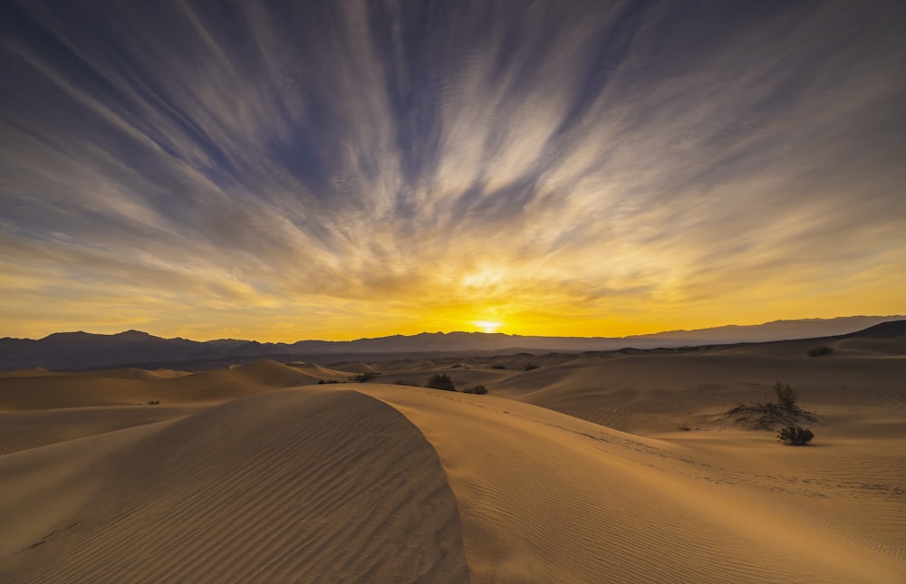 the sun is setting over the sand dunes