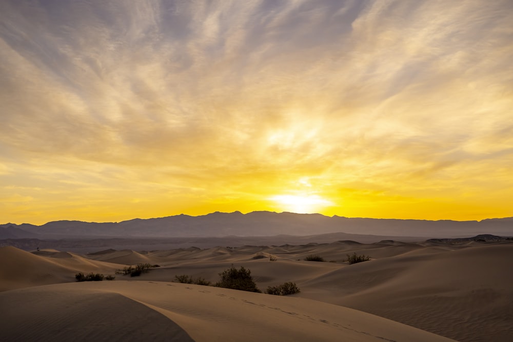 the sun is setting over the sand dunes