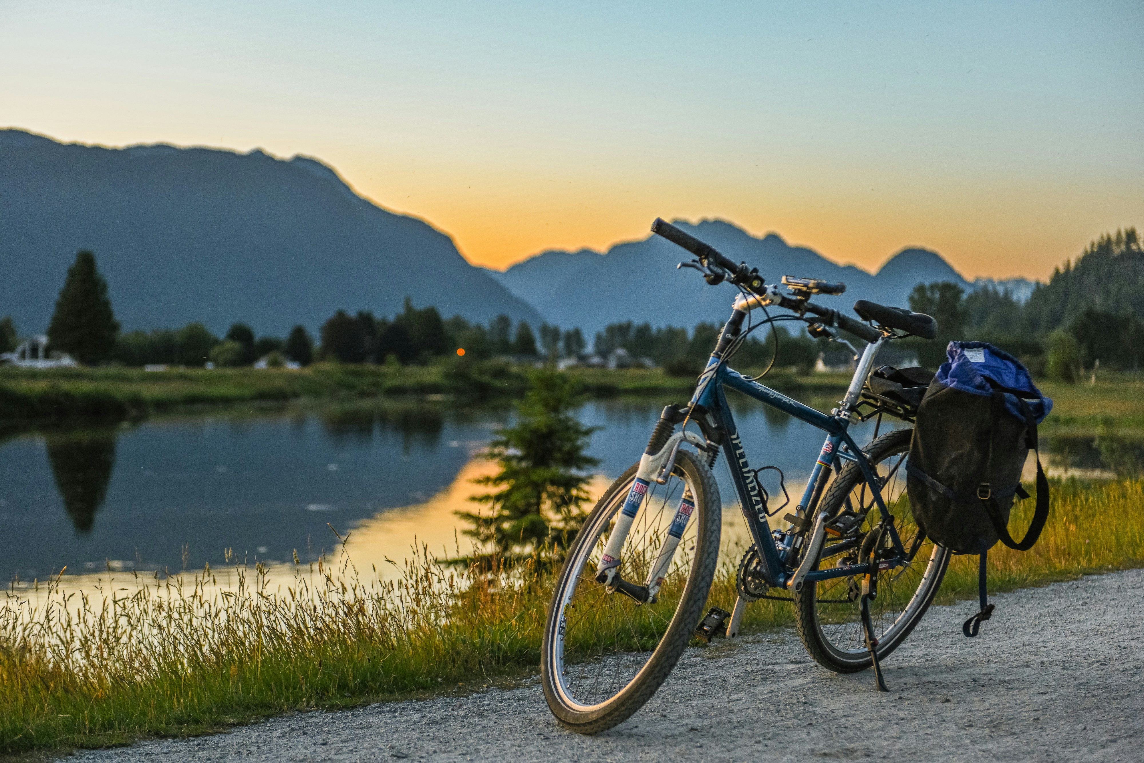 a bicycle parked on the side of a road next to a lake