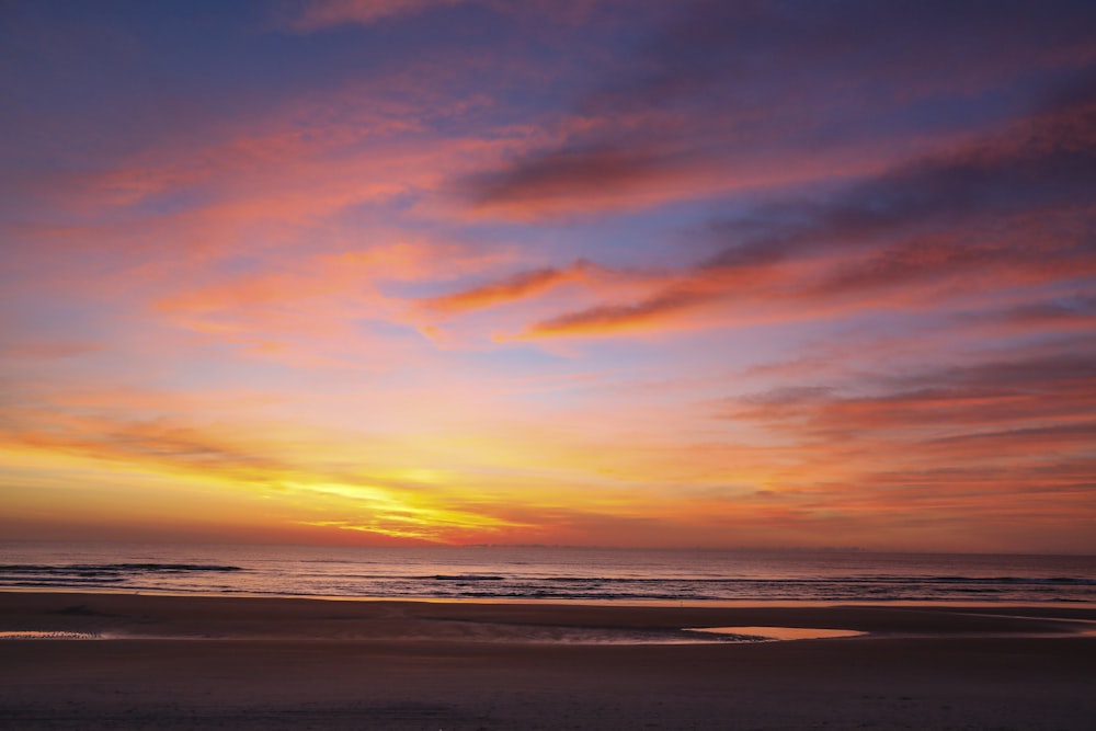 a sunset view of a beach with a surfboard in the foreground