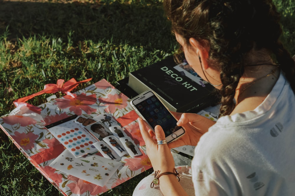 a woman sitting in the grass looking at her cell phone