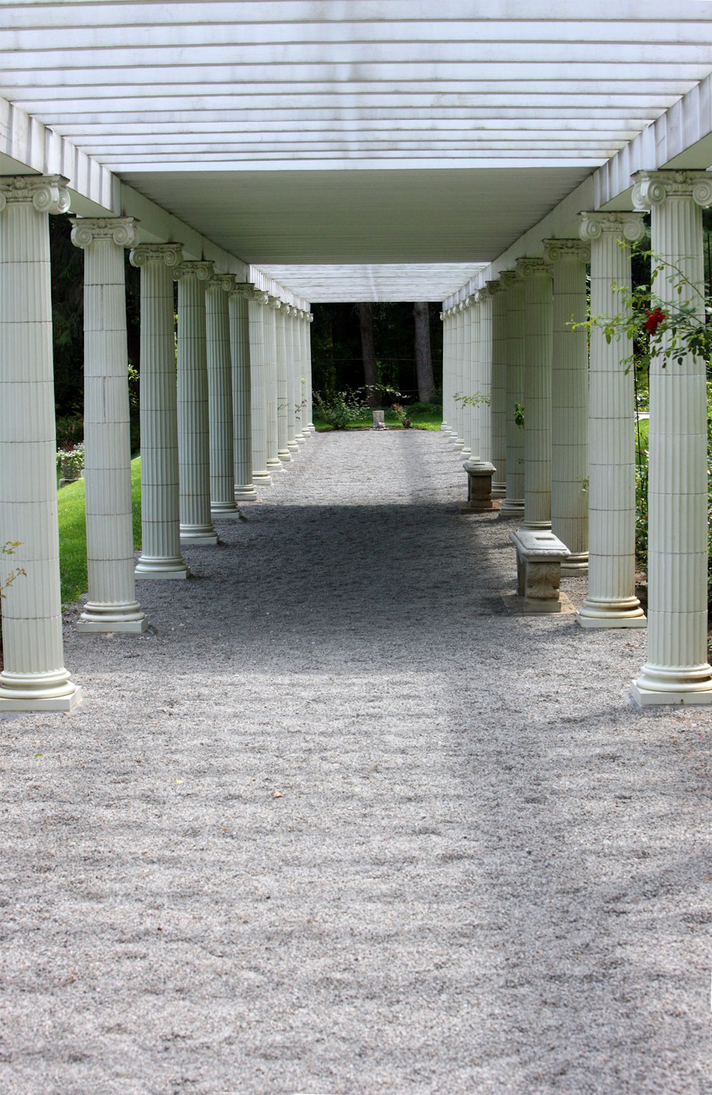 a walkway lined with white columns and benches