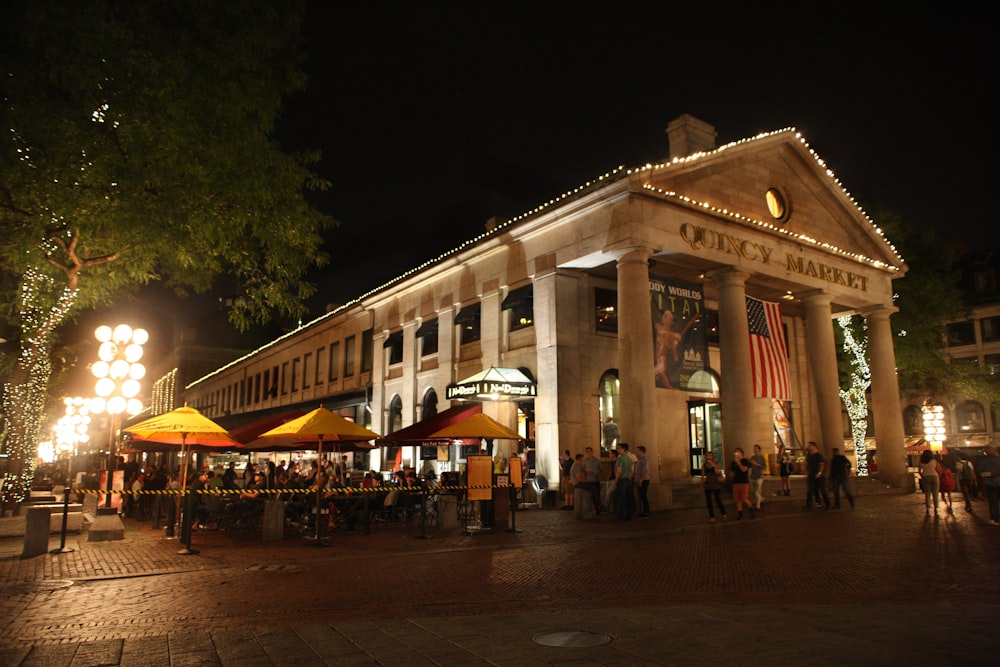 a crowd of people standing outside of a building at night