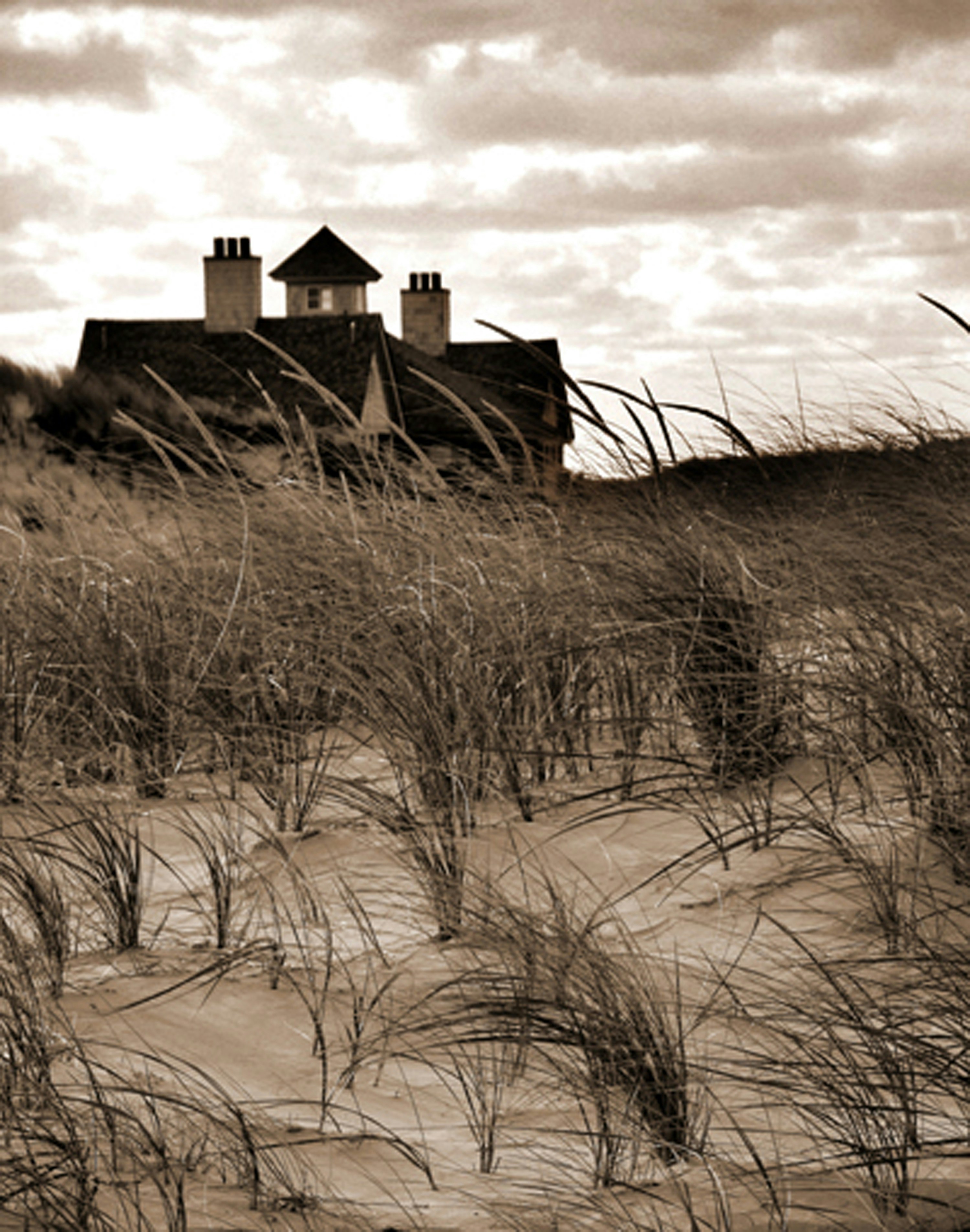 a black and white photo of a house on the beach
