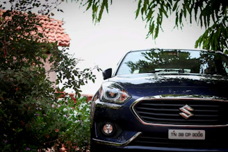 A shiny Suzuki car parked in front of the Rutaviva dealership with lush greenery around.