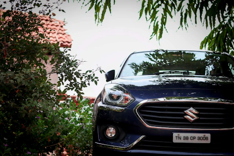 A shiny Suzuki car parked in front of the Rutaviva dealership with lush greenery around.