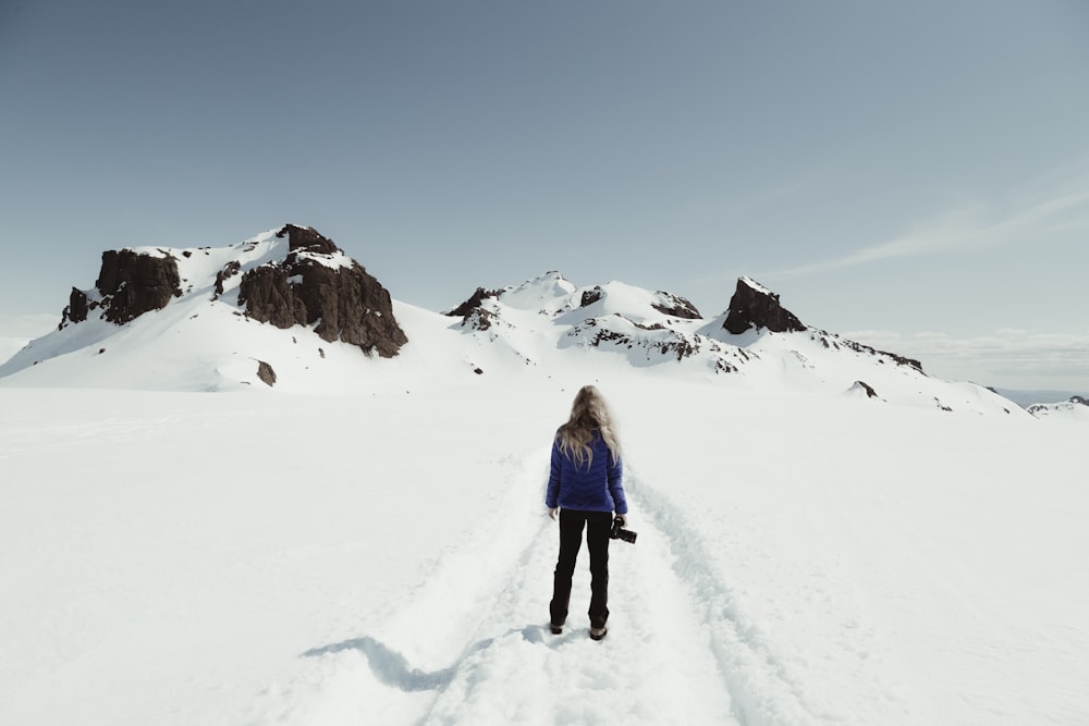 a woman walking across a snow covered field