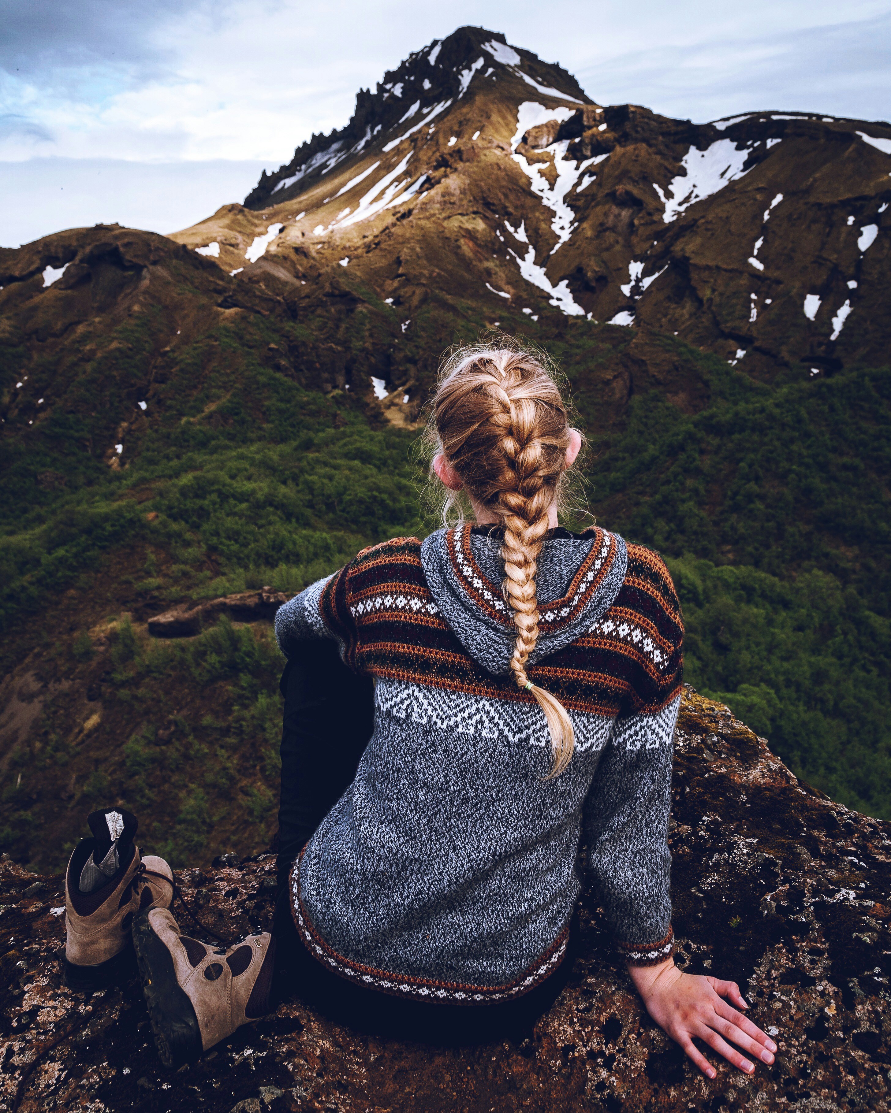 a woman sitting on top of a mountain next to a pair of shoes