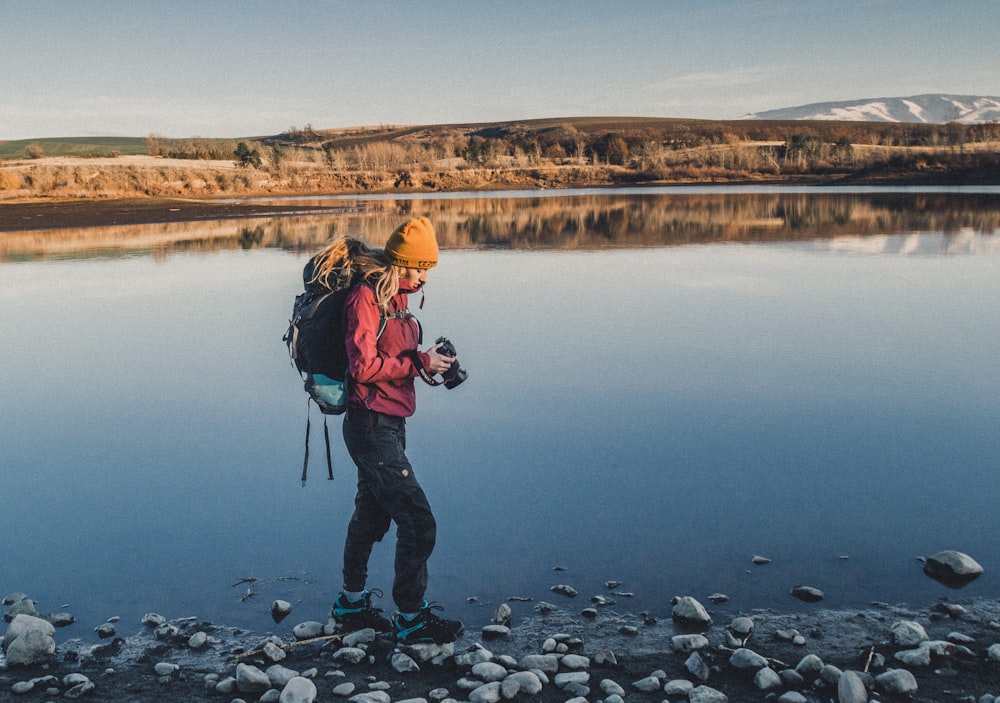 a person with a backpack standing on a rocky shore