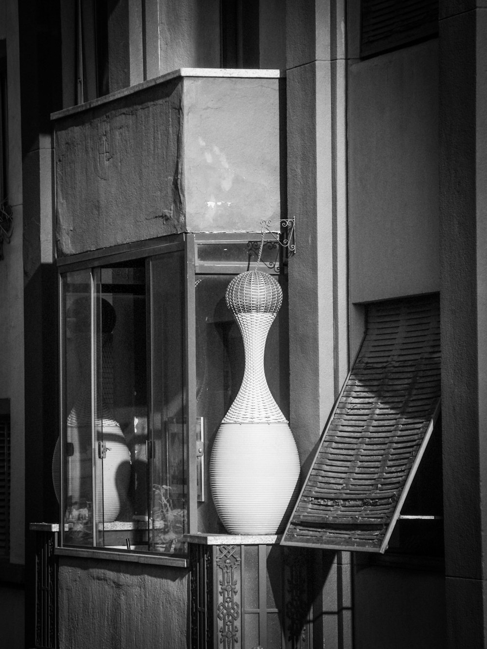 a white vase sitting on top of a table next to a window