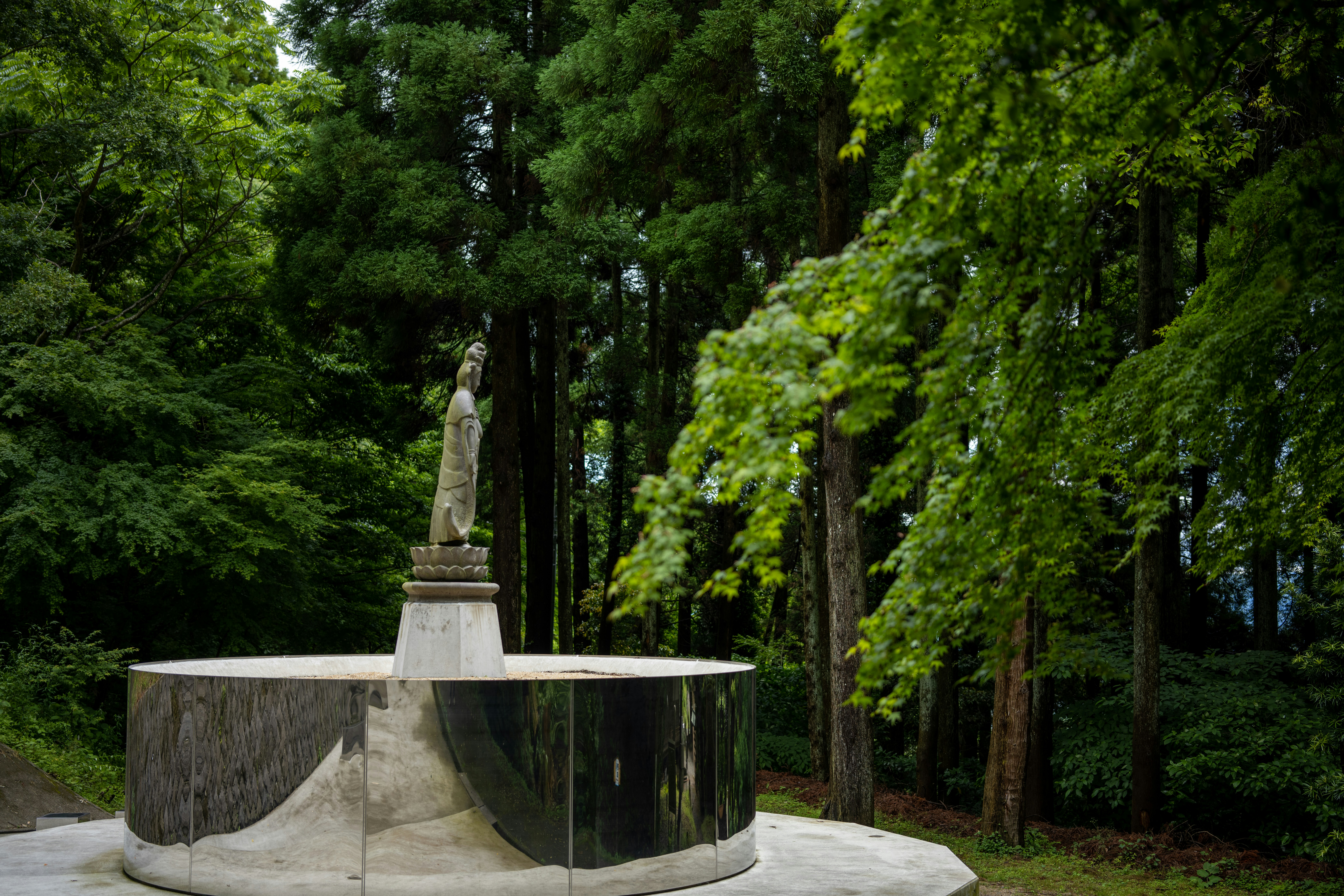 a statue in the middle of a park surrounded by trees